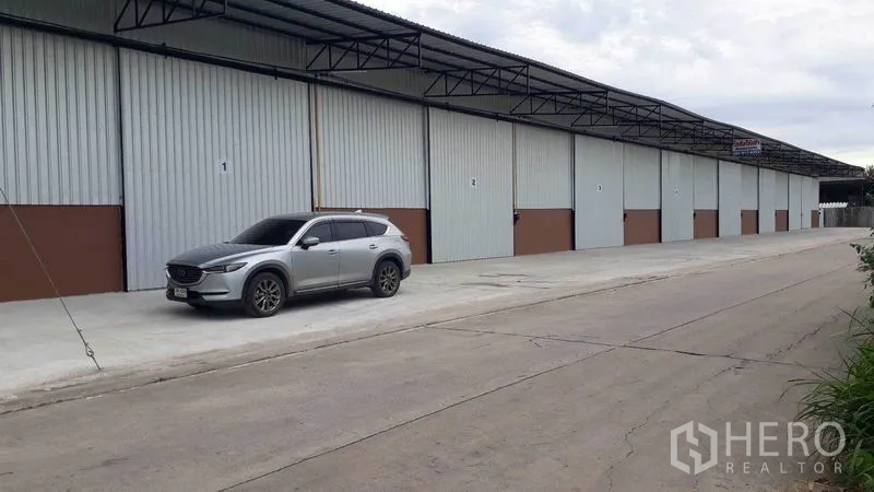 货栈 出租在Khlong Luang, Pathum Thani - 仓库联排外观，带遮雨雨棚与装卸车道，临路停车便利，空銮 巴吞他尼。
