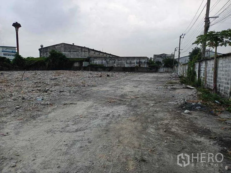 Land for rent in Lat Krabang, Bangkok - Long rectangular plot with boundary walls, compacted ground and overhead utilities along the lane.