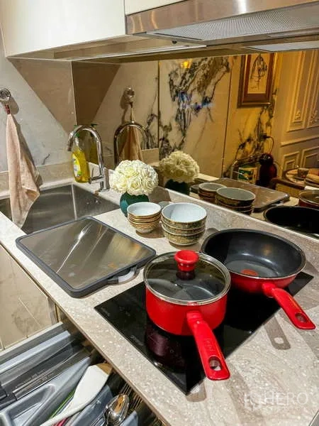 คอนโด ให้เช่า - ครัวขนาดกะทัดรัด ผนังลายหินอ่อน อ่างล้างจาน และเตาอินดักชันพร้อมหม้อสีแดง