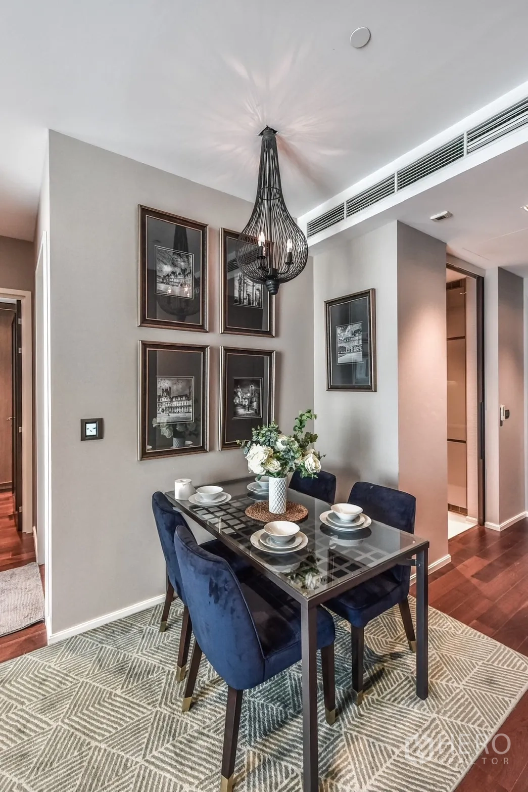 Condominium for rent or sale in Watthana, Bangkok - Four-seat dining set with blue velvet chairs under a modern wire pendant light and framed artwork.