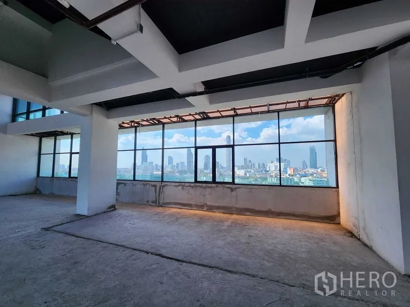 零售空间 出租在Sathon, Bangkok - 纵深开放式零售楼层，连续窗带与外露管线，远眺曼谷市景。