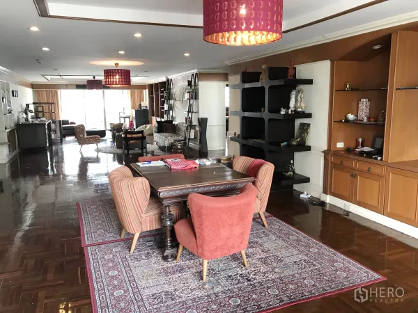 Condominium for rent in Watthana, Bangkok - Open-plan dining and lounge area with oriental rug, wood cabinetry and pendant lighting leading toward large balcony doors.
