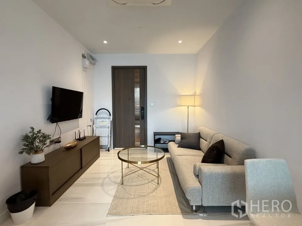 公寓 for rent in Sathon, Bangkok - 现代客厅配灰色沙发、墙面电视、玻璃茶几与落地灯，简约雅致。