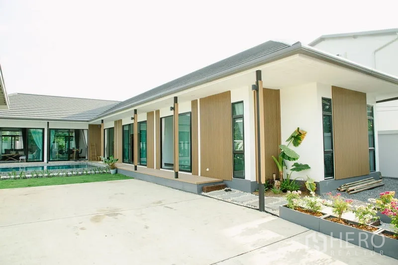 บ้าน ขายในPhra Pradaeng, Samut Prakan - ด้านหน้าบ้านชั้นเดียวสมัยใหม่ แต่งระแนงไม้ หน้าต่างกว้าง และลานคอนกรีต