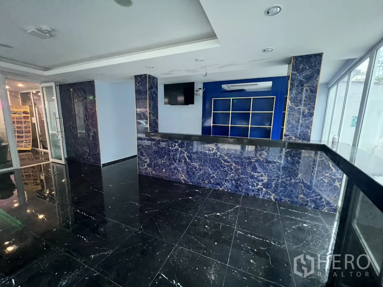 零售空间 出租在Khlong Toei, Bangkok - 前台服务区，蓝色背景墙、内置置物架与宽阔玻璃门面。