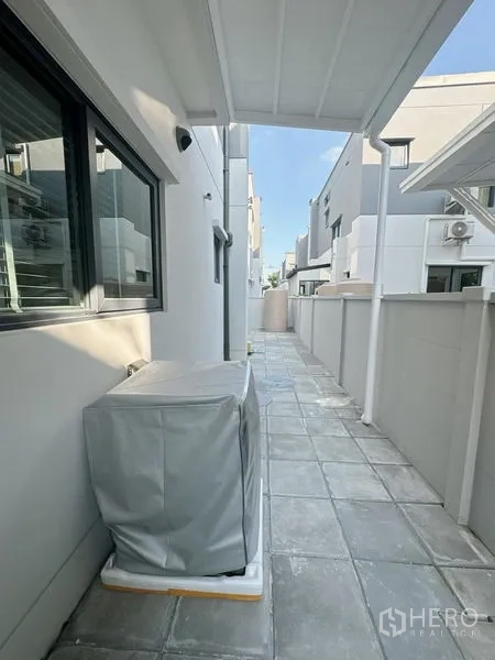 Detached House for rent or sale in Bang Phli, Samut Prakan - Covered side walkway with tiled floor and outdoor utility area beside the house.