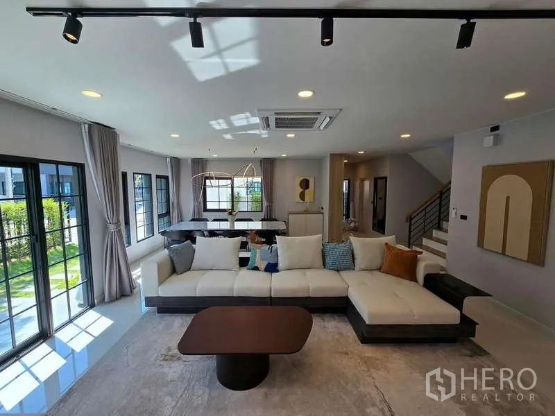 Detached House for rent in Bang Phli, Samut Prakan - Sectional sofa living room connecting to dining area and staircase.