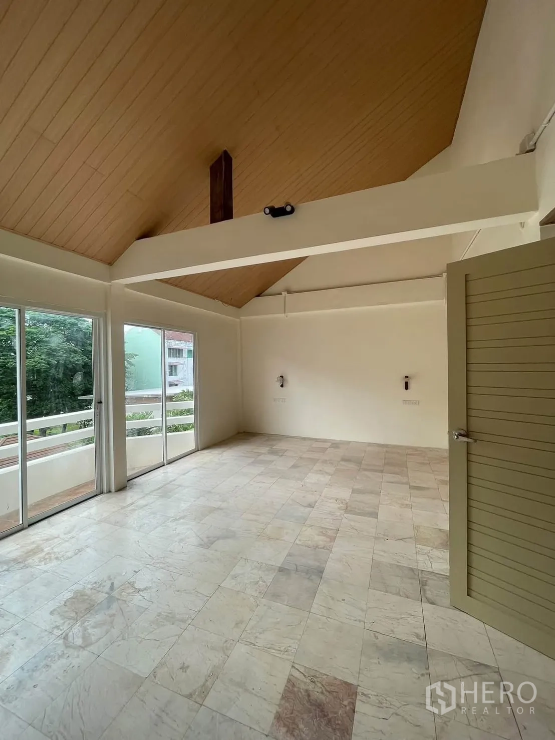 ทาวน์เฮาส์ for rent in Huai Khwang, Bangkok - พื้นที่นั่งเล่นโปร่งเพดานสูงกับคานไม้ พื้นกระเบื้อง และประตูกระจกบานเลื่อนออกสู่ระเบียง.