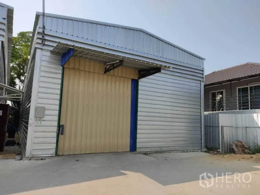 Warehouse for rent in Bang Phli, Samut Prakan - Front exterior of the warehouse with tall rolling door and loading canopy.