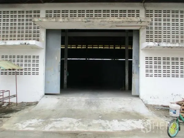 Warehouse for rent in Min Buri, Bangkok - Loading bay with ramp and large sliding doors opening into the warehouse storage area.