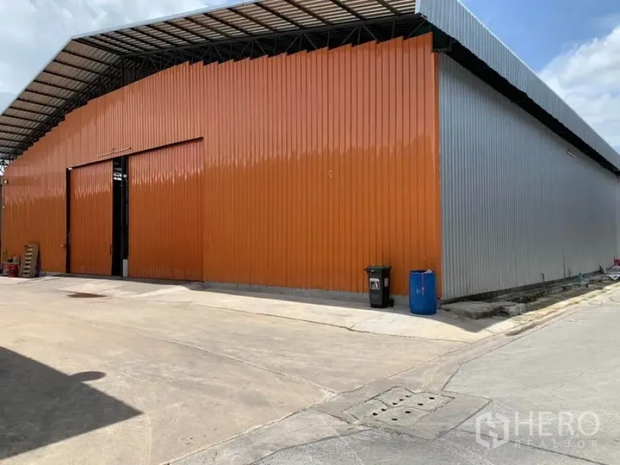 Warehouse for rent in Bang Kapi, Bangkok - High-clearance warehouse exterior with orange steel cladding and a wide sliding door in Bang Kapi, Bangkok.