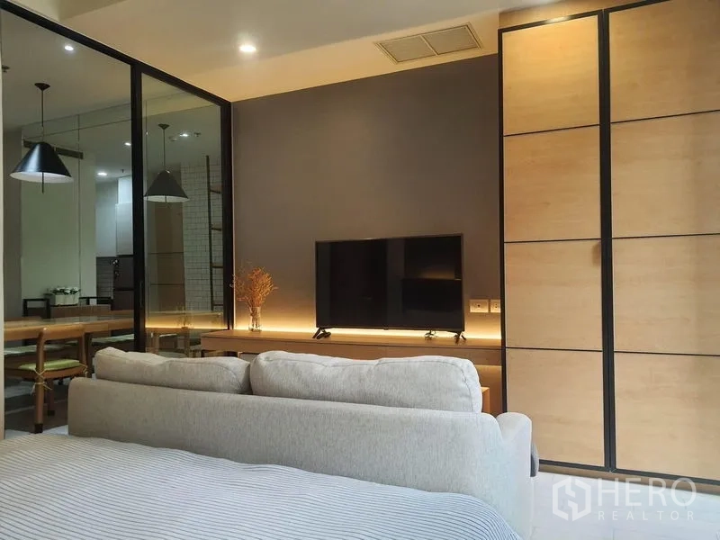 คอนโด ให้เช่าในPathum Wan, Bangkok - ผนังทีวีพร้อมแสงไฟซ่อนสว่างไออุ่น มองจากเตียงนอนและตู้บิลต์อินดีไซน์ทันสมัย