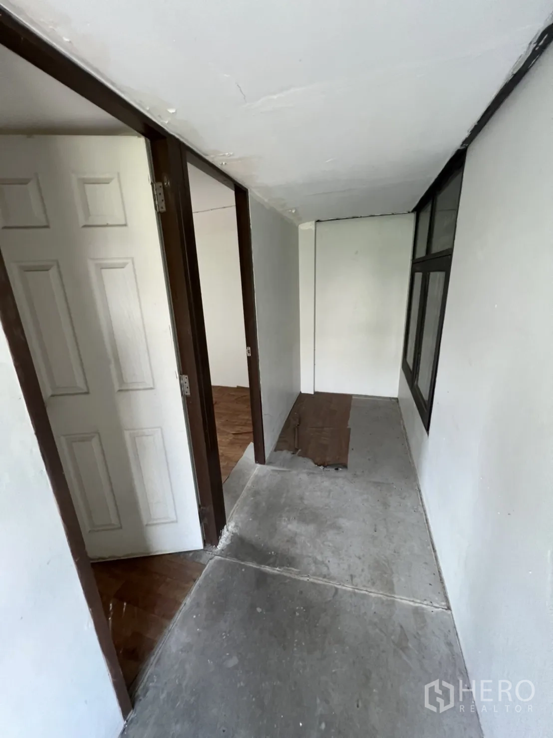 Home Office for rent in Watthana, Bangkok - Narrow corridor with wooden floorboards and a window at the end.