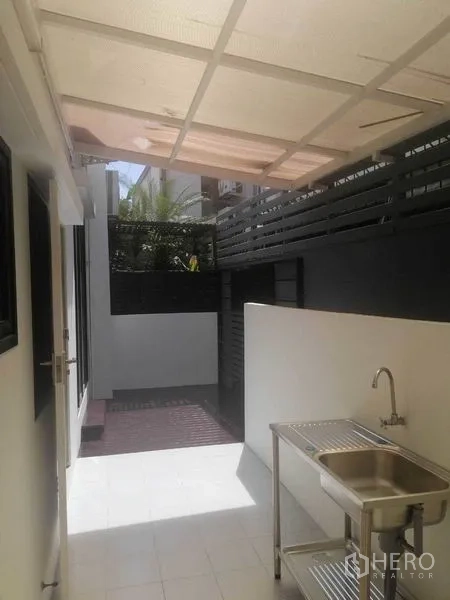 Townhouse for rent in Wang Thonglang, Bangkok - Covered outdoor utility area with stainless-steel sink and tiled floor.