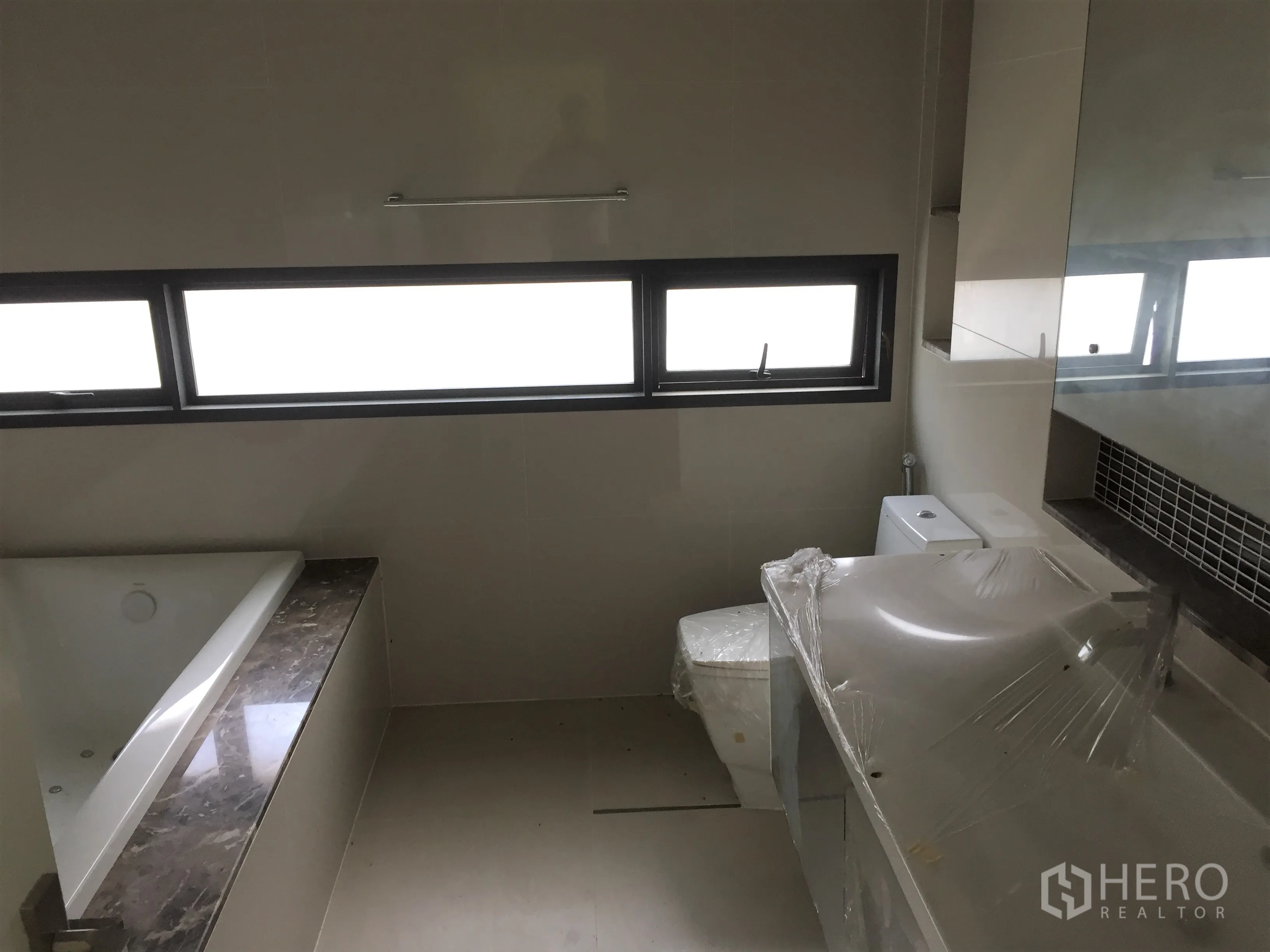 Detached House for rent or sale in Prawet, Bangkok - Bathroom featuring a bathtub, long vanity and horizontal windows.