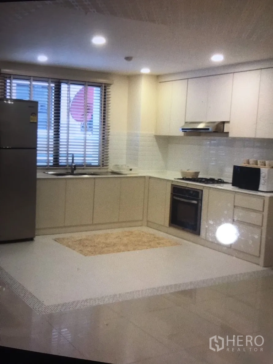 公寓 出租在Bang Rak, Bangkok - 厨房另一视角，带不锈钢冰箱、充足柜体与百叶窗。