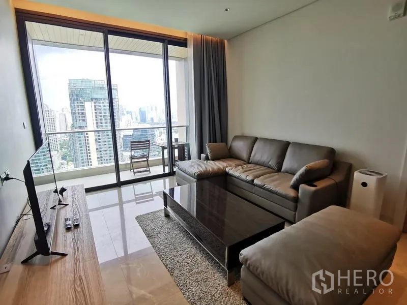 Condominium for rent in Pathum Wan, Bangkok - Living room with TV console, sectional sofa and balcony showcasing Bangkok views.