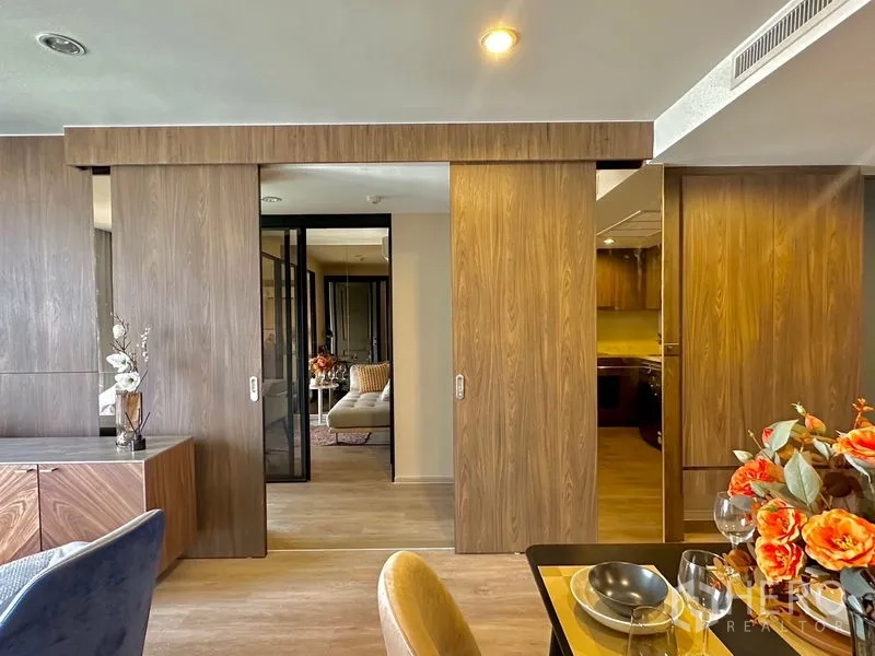 คอนโด ให้เช่าในPathum Wan, Bangkok - ประตูบานเลื่อนไม้เปิดไปยังห้องนอนพร้อมไฟโทนอุ่นและตู้เก็บของ