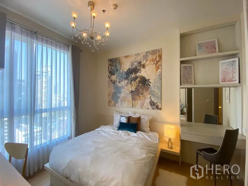 Condominium for rent or sale in Khlong Toei, Bangkok - Bright bedroom with large window, vanity desk and soft drapes overlooking the city.
