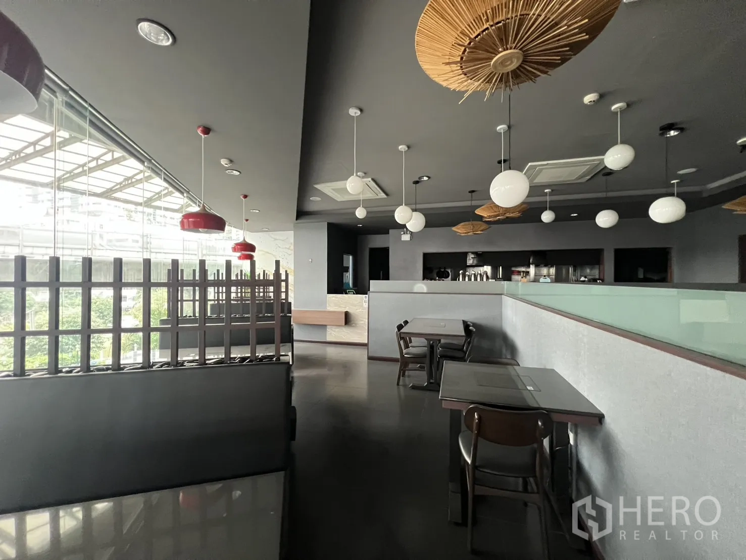 零售空间 for rent in Watthana, Bangkok - 商铺配整面玻璃立面、嵌入式空调与木质细节，设有桌椅并可眺望绿意。