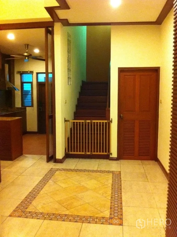 Townhouse for rent or sale in Watthana, Bangkok - Entrance hall with tiled inlay flooring and staircase adjacent to the kitchen.