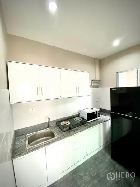 ทาวน์เฮาส์ ให้เช่าในPrawet, Bangkok - ครัวบิวต์อินตู้สีขาว เคาน์เตอร์หิน อ่างล้างจาน เตาอบไมโครเวฟ และตู้เย็นขนาดใหญ่.