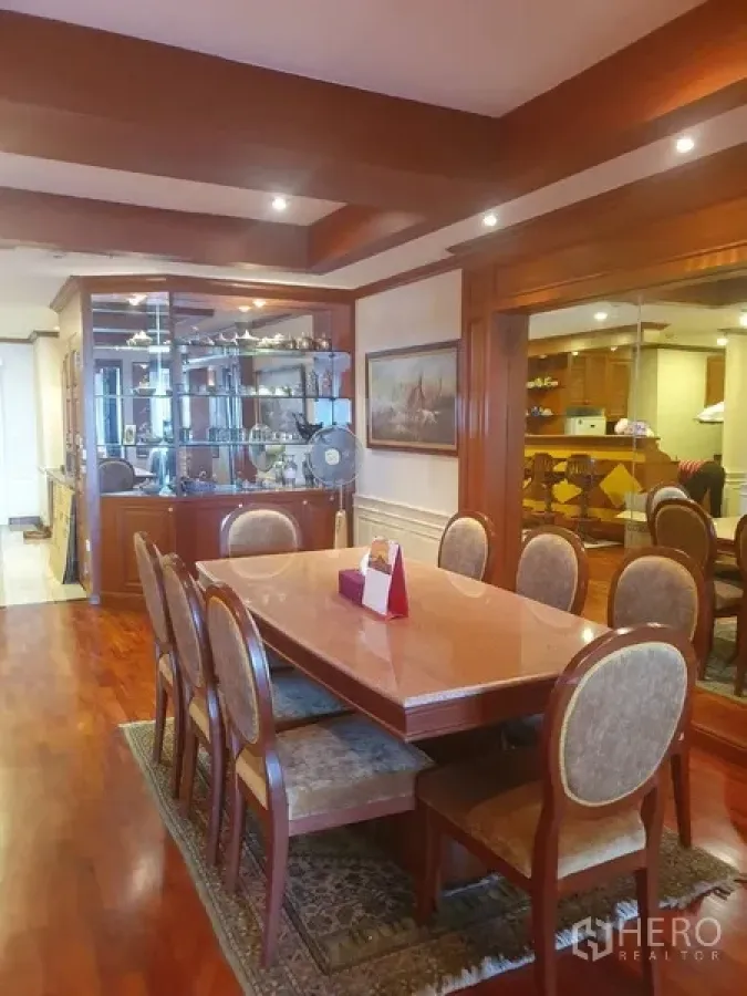 Condominium for rent in Bang Kho Laem, Bangkok - Formal dining area with eight-seat wooden table, glass display cabinet, recessed lighting and polished hardwood floors.