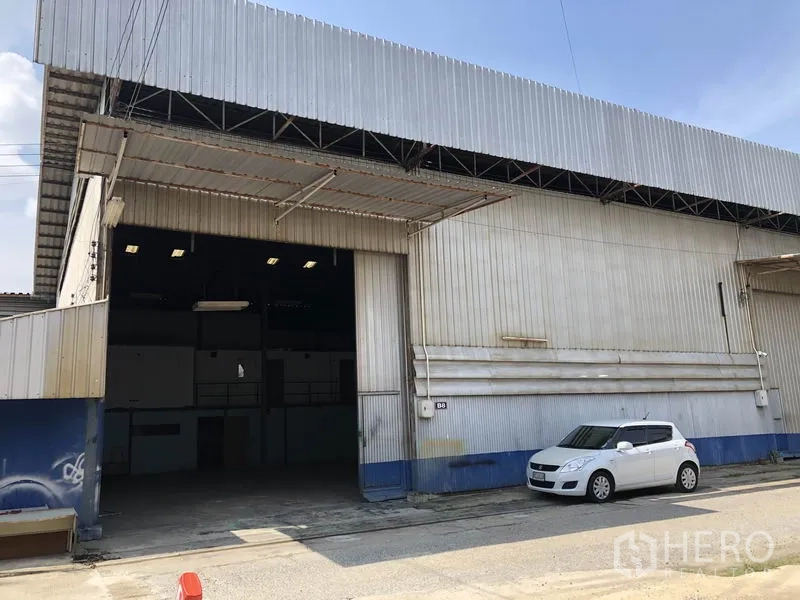 Warehouse for rent in Lam Luk Ka, Pathum Thani - Front elevation of a warehouse bay with wide opening shutter, canopy roof and parking space.