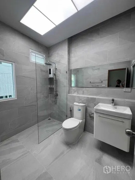 Townhouse for rent in Khlong Toei, Bangkok - Contemporary bathroom with walk-in glass shower, large mirror and window.