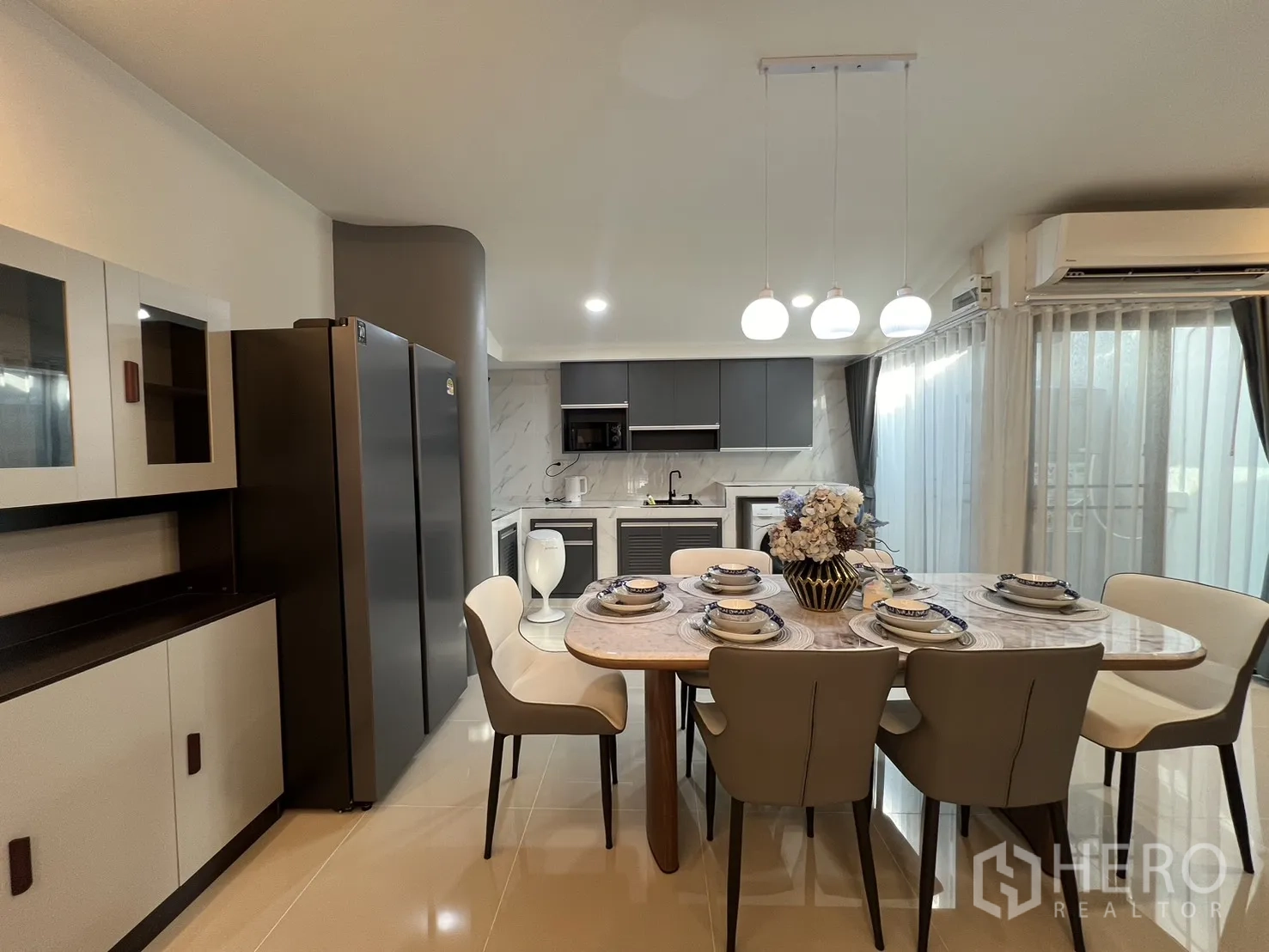 Townhouse for rent in Bang Phli, Samut Prakan - Marble-top dining table set for six beside a double-door fridge and storage cabinet.