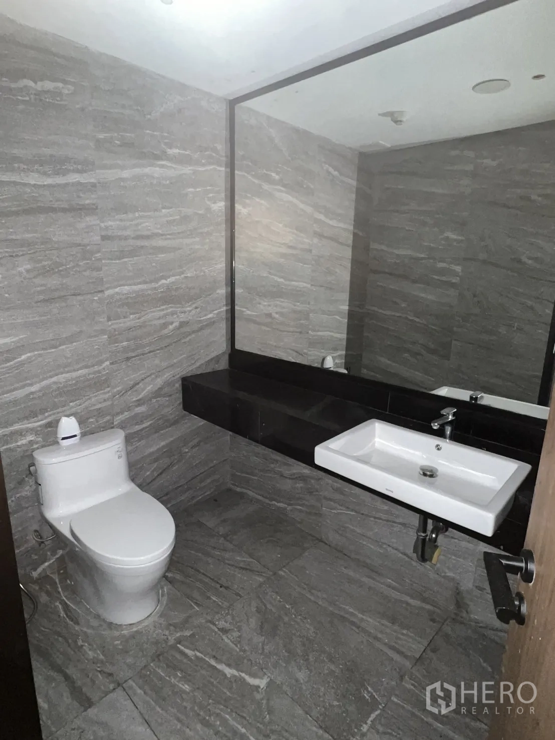 พื้นที่ขายปลีก ให้เช่าในWatthana, Bangkok - ห้องน้ำอีกห้อง กระจกบานใหญ่ ผนังลายหิน และอุปกรณ์สุขภัณฑ์สีขาว