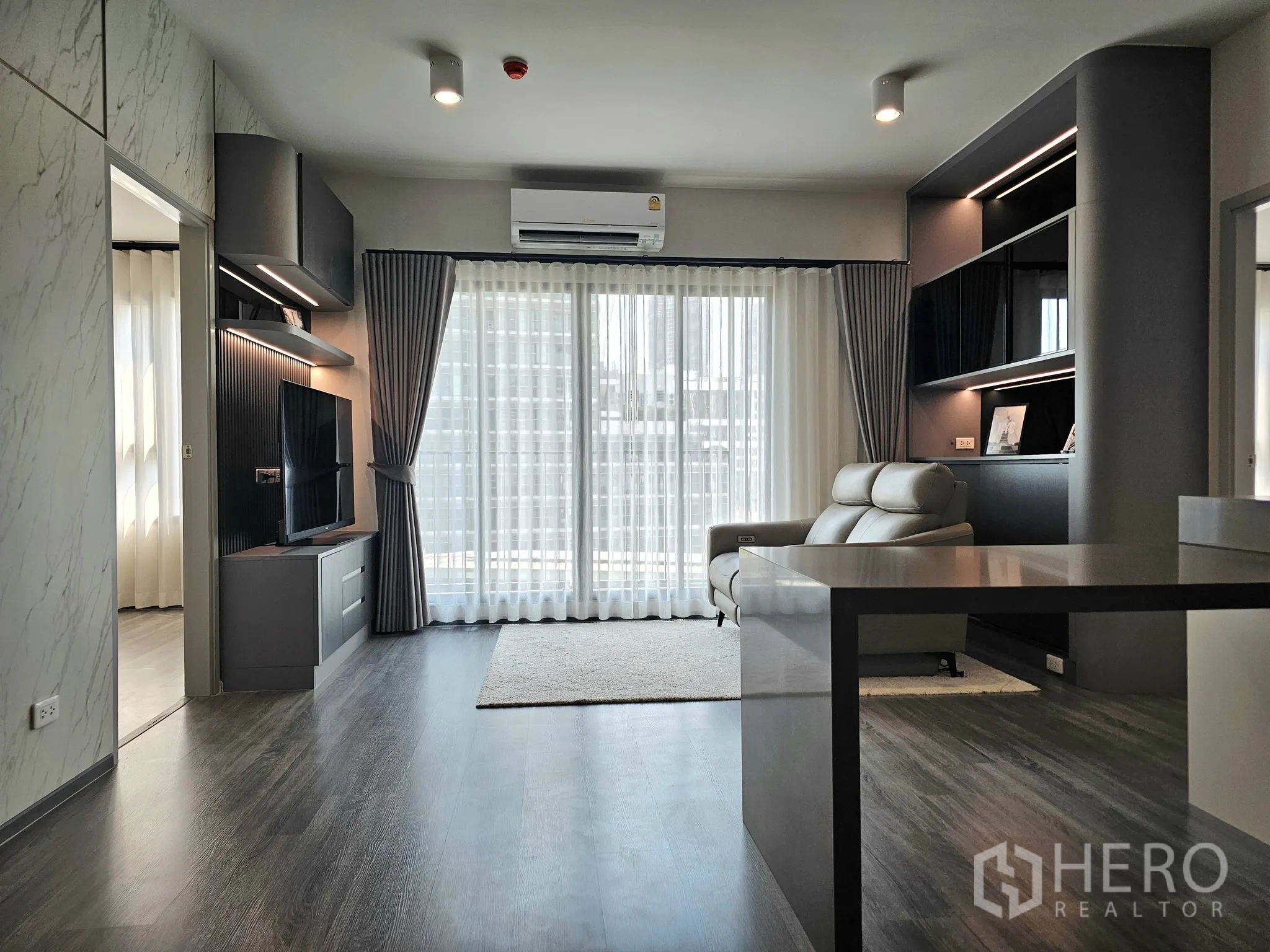 คอนโด for sale in Bang Rak, Bangkok - ห้องนั่งเล่นสไตล์โมเดิร์น ผนังทีวีพร้อมชั้นบิลท์อินและประตูกระจกบานเลื่อนขนาดใหญ่