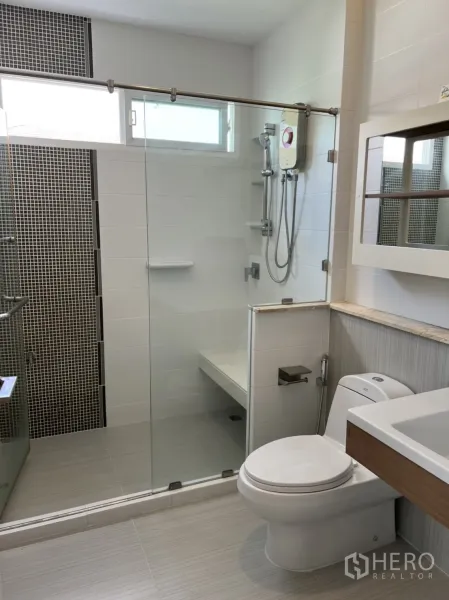 Detached House for rent in Bang Kapi, Bangkok - Modern bathroom featuring a glass shower enclosure, water heater, vanity, and toilet.