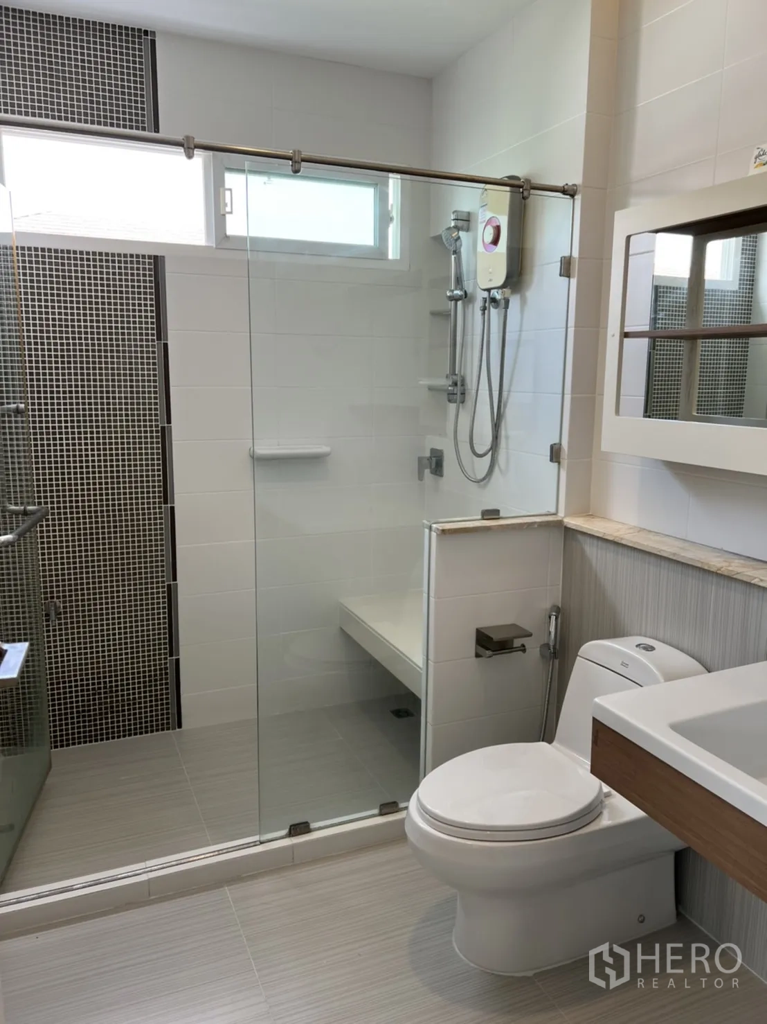 Detached House for rent in Bang Kapi, Bangkok - Modern bathroom featuring a glass shower enclosure, water heater, vanity, and toilet.