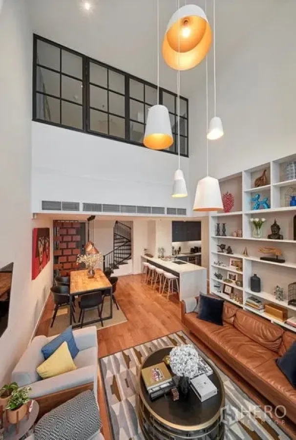 คอนโด ให้เช่าหรือขายในSathon, Bangkok - ห้องนั่งเล่นเพดานสูงพร้อมโคมแขวน ชั้นวางบิวท์อิน โซฟาหนัง โต๊ะทานข้าว บันไดวน และครัวพร้อมบาร์