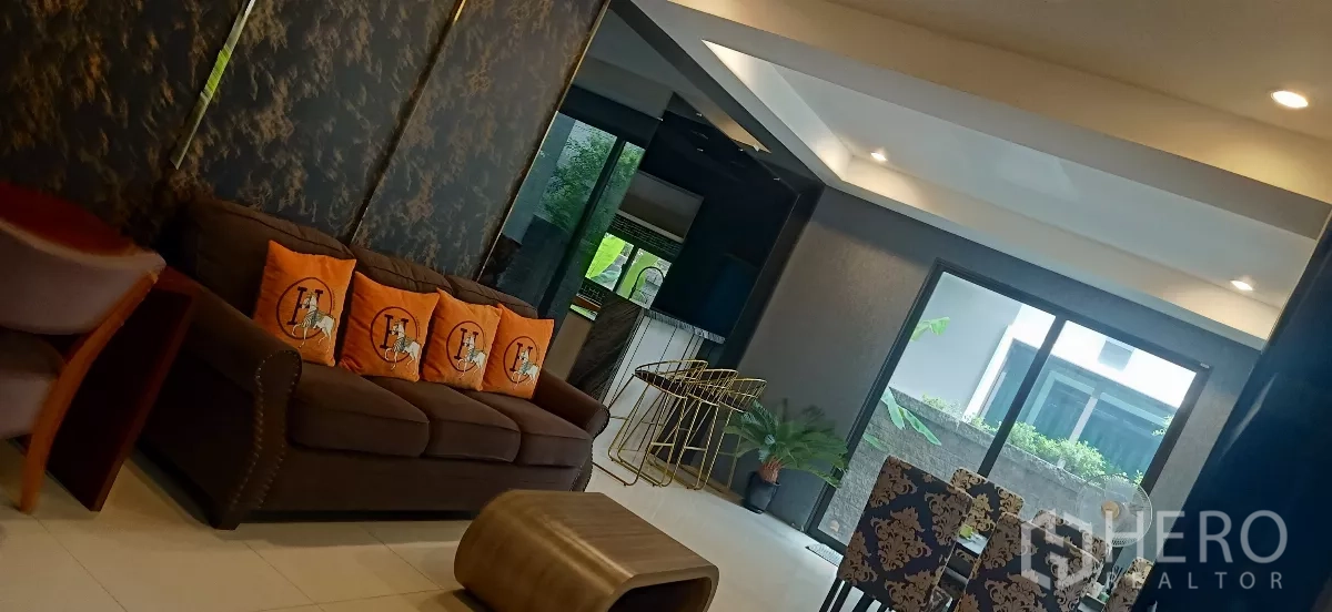 บ้าน ให้เช่าหรือขายในKhan Na Yao, Bangkok - โถงนั่งเล่นและรับประทานอาหารแบบเปิดโล่ง โซฟาสีน้ำตาล เคาน์เตอร์บาร์ และประตูกระจกสไลด์ออกสวน