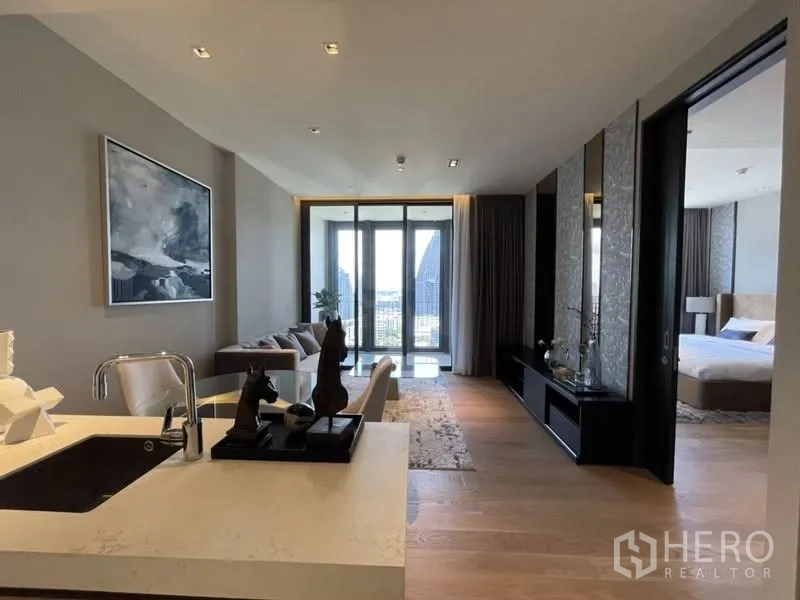 Condominium for rent or sale in Khlong Toei, Bangkok - Kitchen viewpoint over the open living space toward the balcony, with bedroom accessed via sliding door.