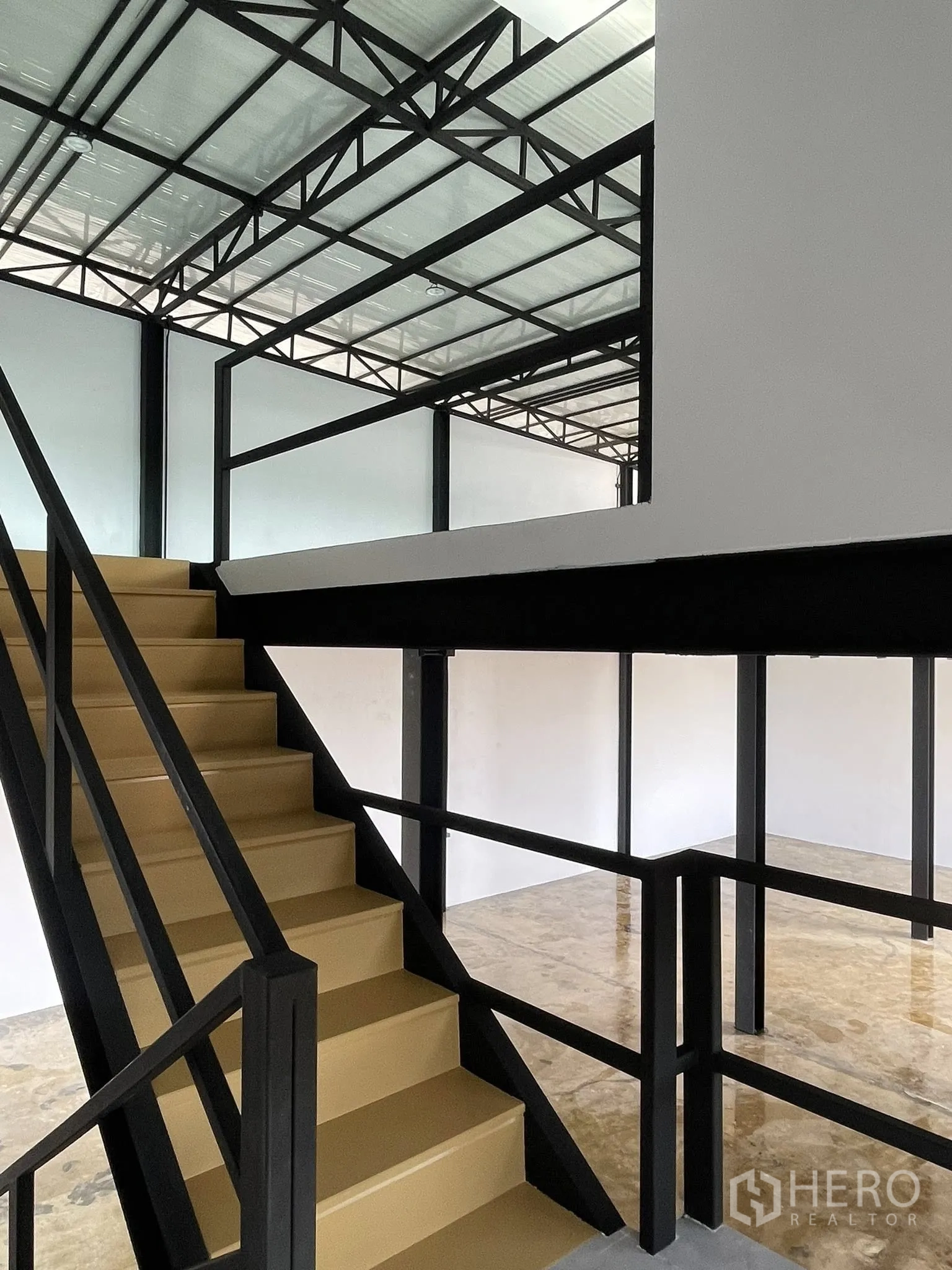 Warehouse for rent in Phra Samut Chedi, Samut Prakan - Close-up of steel staircase and mezzanine framing beneath insulated roof panels.