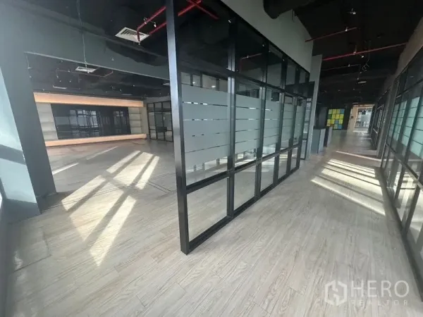 Office Space for rent in Bang Rak, Bangkok - Corridor with full-height glass partitions and frosted stripes, opening to a bright office area.
