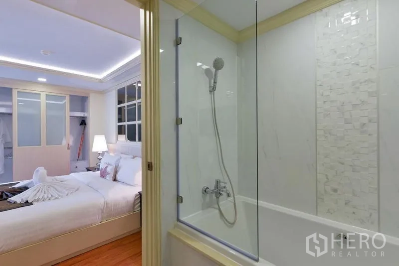 房间 出租在Khlong Toei, Bangkok - 从浴室望向卧室，可见玻璃浴缸与明亮睡眠区。