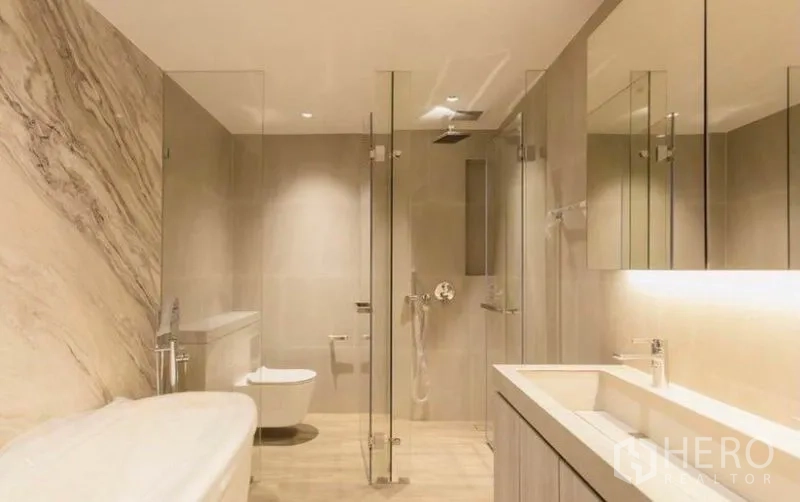 公寓 出租在Bang Rak, Bangkok - 现代卫浴，设浴缸、玻璃淋浴间与背光梳洗台，暖色石材。