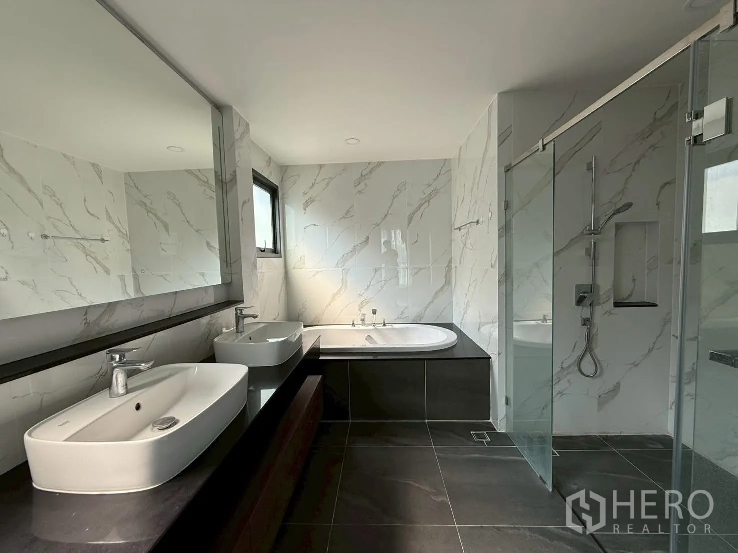Townhouse for rent - Luxury bathroom featuring double vanity, bathtub, marble‑effect tiles and a glass shower.
