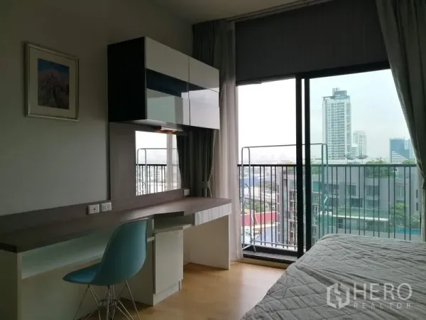 Condominium for rent in Watthana, Bangkok - Work desk and wall cabinets beside sliding glass doors to a balcony with skyline views.