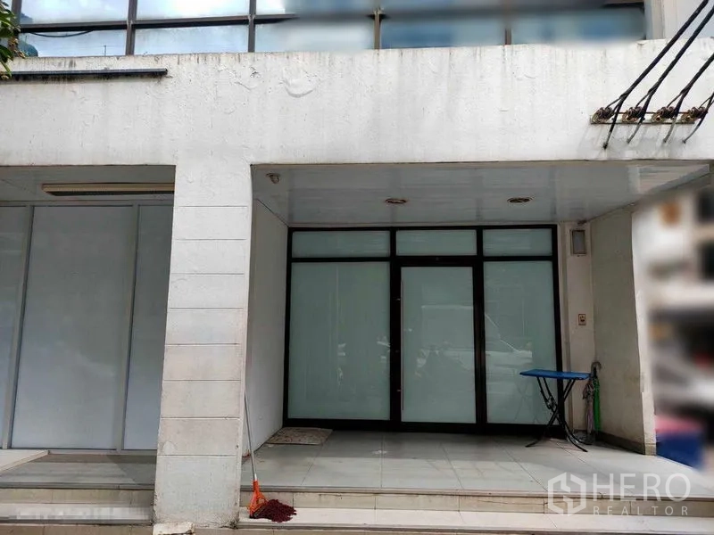 店屋 出租在Watthana, Bangkok - 通罗区域商铺一层外立面，磨砂玻璃门、瓷砖门廊与遮雨檐，外观整洁现代。