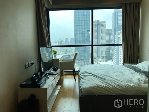 公寓 出租或出售在Bang Rak, Bangkok - 卧室设落地窗与木地板，书桌与电视柜面向城市景观。