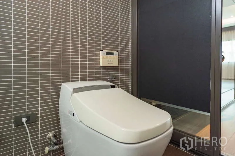 联排别墅 出租或出售在Lat Phrao, Bangkok - 智能马桶置于条纹瓷砖墙前。