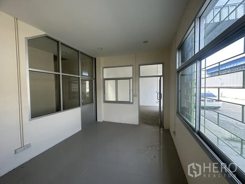 Warehouse for rent in Pathum Thani - Ground‑floor glass‑partitioned office with large windows overlooking the driveway.