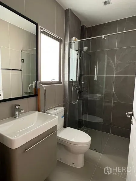 บ้าน ให้เช่าในBueng Kum, Bangkok - ห้องน้ำสมัยใหม่พร้อมหน้าต่าง ฝักบัวกั้นกระจก กระเบื้องโทนเทา อ่างล้างหน้าและโถสุขภัณฑ์