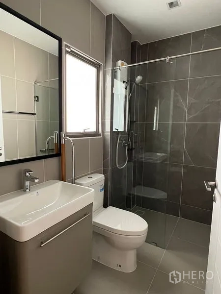 บ้าน ให้เช่าในBueng Kum, Bangkok - ห้องน้ำสมัยใหม่พร้อมหน้าต่าง ฝักบัวกั้นกระจก กระเบื้องโทนเทา อ่างล้างหน้าและโถสุขภัณฑ์