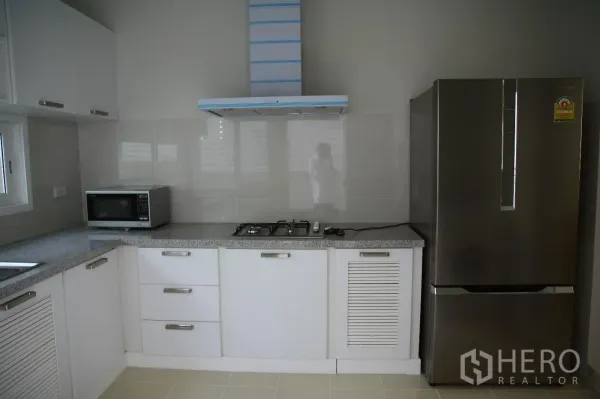 Detached House for rent or sale in Bang Na, Bangkok - Fitted kitchen with white cabinets, granite countertop, gas hob, range hood, microwave and stainless refrigerator.